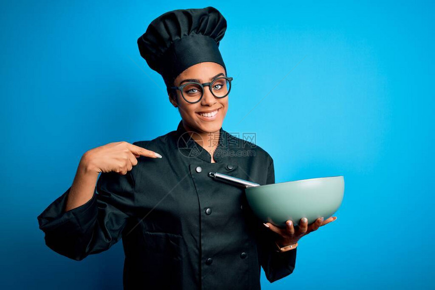 身着烹饪制服和帽子的年轻非洲女厨师女孩使用胡须和碗盘图片