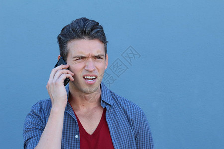 英俊年轻男子在蓝墙前通过电话交背景图片