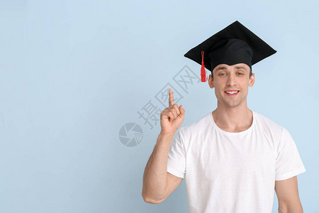 戴着毕业帽子的年轻男子和在光背景上举高了食图片