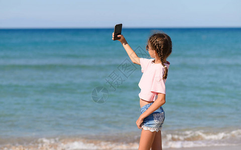 一个女孩站在海边的沙滩上自拍一个现代女孩在海边图片