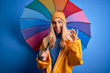 下雨天穿着雨衣的金发美女拿着五颜六色的雨伞图片