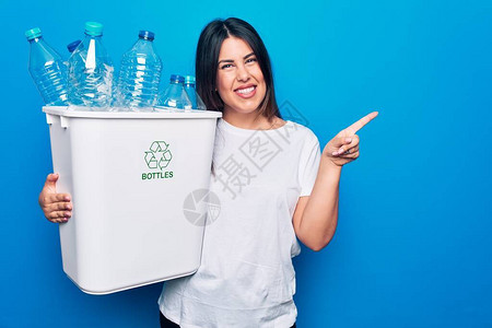 年轻漂亮的女人在废纸篓上回收塑料瓶来关心环境图片