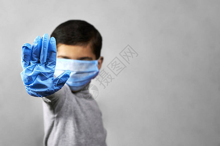 戴着医用口罩和防护手套的7岁中东男孩展示手势图片