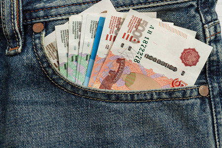 从蓝色牛仔裤口袋里伸出的钞票背景图片