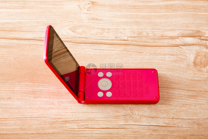 红色手机在木制桌子上将侧道图片