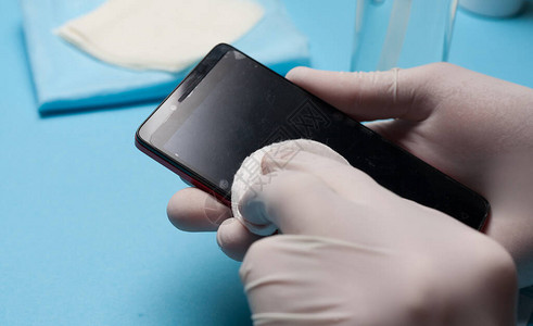 用白手套清洁智能手机预防冠状感染特写消毒图片