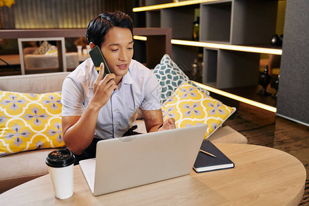 英俊的亚洲青年商人在笔记本电脑屏幕上阅读合同图片