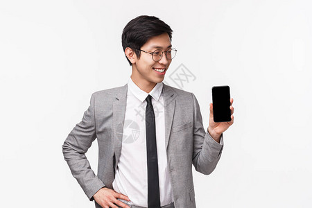 自豪的专业年轻亚洲男上班族企业家的腰部肖像介绍了他的手机应用程序图片