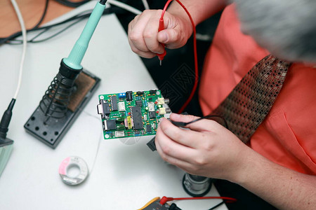 一个人的手从事工具维修电子服务制造焊接电路板的手动组装图片