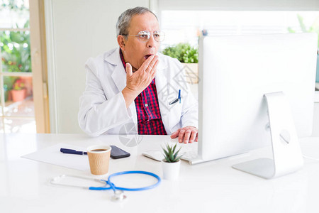 从事研究的英俊高级医生男子使用笔记本电脑在诊所寻找治疗方法图片