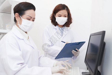大声疾阅读牙科医阅读医疗记录和护士在计算图片
