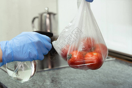 戴手套的手在厨房的袋子里消毒西红柿图片