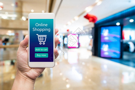 智能手机在线购物在女人手中背景中的购物中心通过电子商务网站购买图片