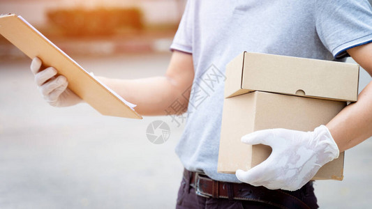 一名送货员在客户家门前拿着包裹和箱子图片