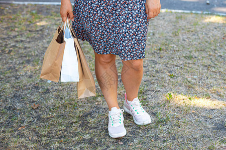 女手拿着纸购物袋在街上的公园里图片