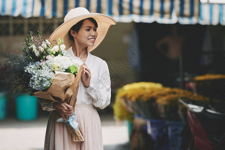 穿着夏帽的漂亮女人拿着花束背景图片