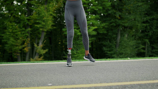 残疾妇女在路上侧身跳跃适合女孩在慢动作中在柏油路上跳跃积极的跑步者独图片