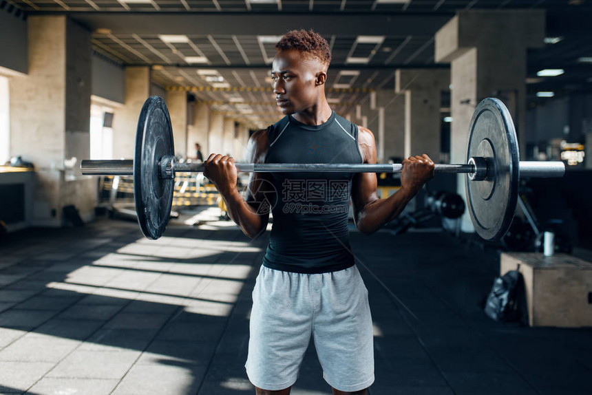 穿着运动服的肌肉运动员在健身房训练时用杠铃锻炼图片