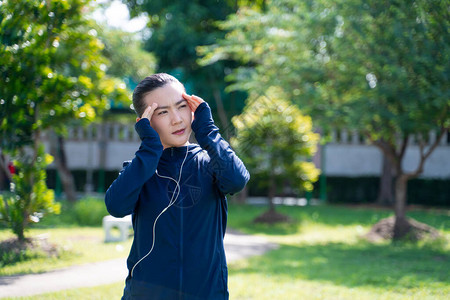 亚洲女人的肖像在公园听音乐时头痛在公园锻炼的女图片