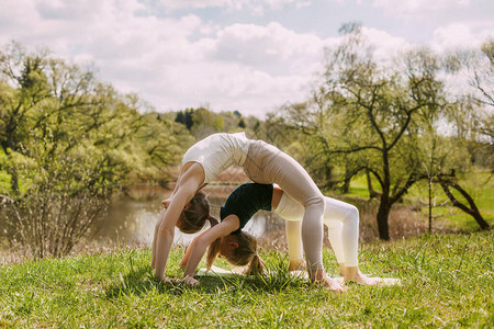 年轻的母女在公园的露天做瑜伽一个女孩和她的女儿一起做操图片