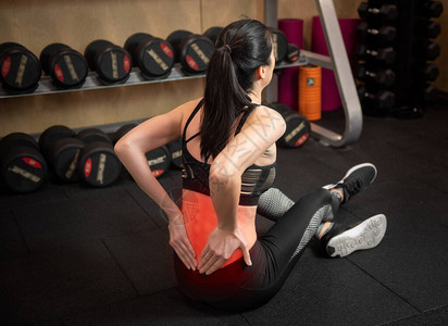 在健身房锻炼时背痛的女人图片