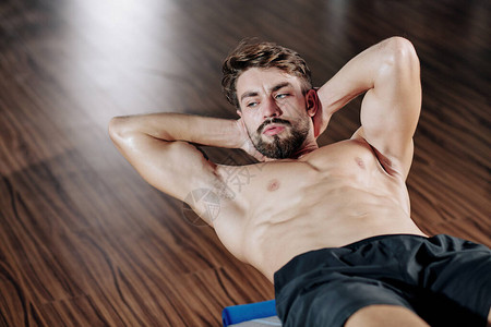 有吸引力的肌肉有色胡子的年轻男子在健身房做坐图片