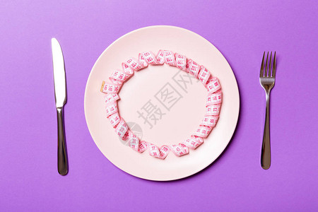 两边用紫色背景的叉子和刀子盘子上的测量磁带减肥概念图片