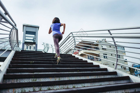 一个女人跑上楼梯在城市进行跑步训练跑步达到目标对胜利的渴望图片
