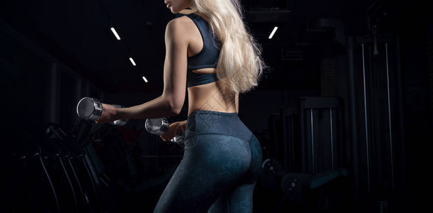 迷人的女运动员在健身房里用哑铃摆姿势健美健身伸展健康饮食的概腹肌高清图片素材