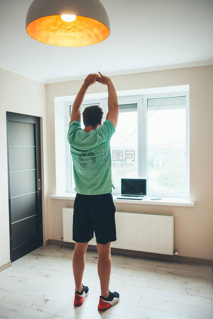 高的caucasian男子伸展身体和练习家庭健身图片