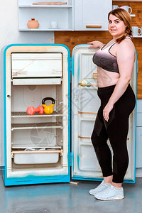 冰箱架子上的哑铃和壶铃的照片胖女人站在冰箱旁图片