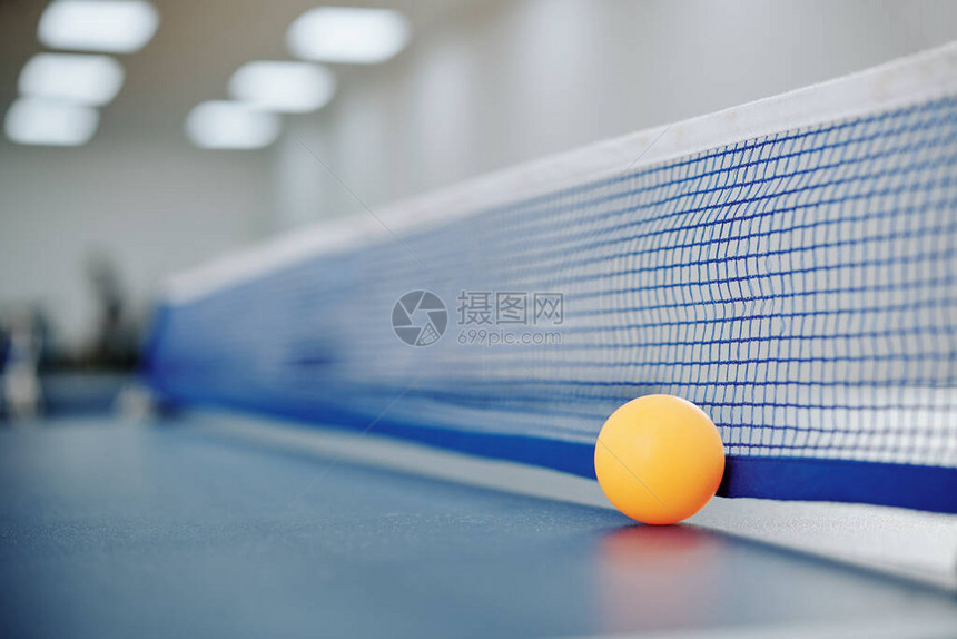 网球桌网旁的橙色小乒乓球图片