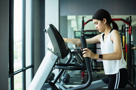 亚洲女孩在健身房进行椭圆有氧运动锻炼图片