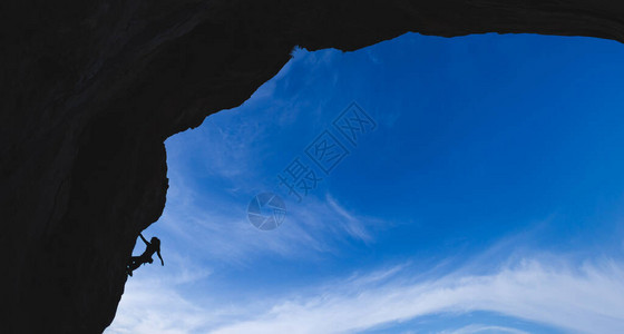 攀岩者攀登拱形岩石的剪影图片