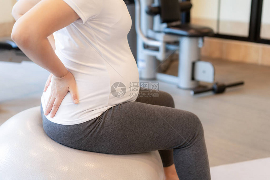 活跃的孕妇在瑜伽室的健身中心锻炼年轻的准妈抱着婴儿在怀孕的肚子里产前护理和图片