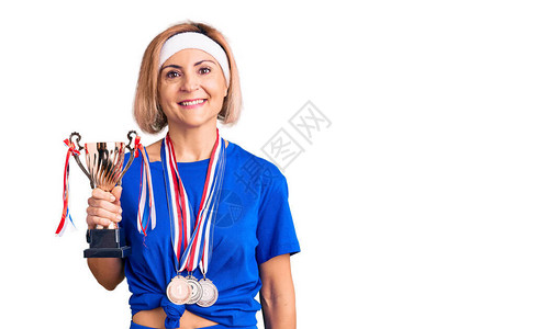 年轻的金发女子捧着冠军奖杯图片