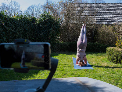 在花园做瑜伽锻炼的年轻女子瑜伽姿势在三脚架图片