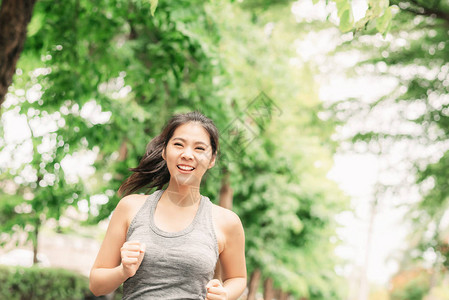 快乐的年轻健康亚裔女在公园户外跑步慢跑训嬉戏的高清图片素材