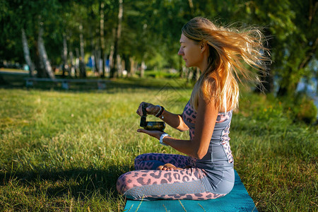 一位身穿粉灰色紧身衣的纤细金发女郎坐在大自然中背景图片