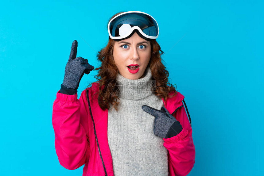 穿着滑雪眼镜的滑雪女人在隔绝的蓝色墙壁上面部出图片