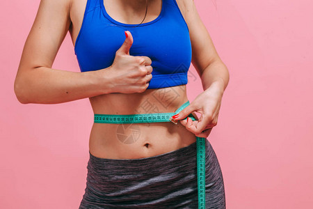 瘦的女生用腰部测量腰部在粉红背图片