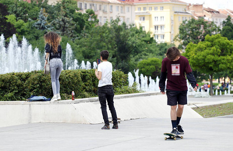 年轻人或青少年在公园里玩得开心滑板和拍照图片