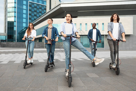5名兴奋的散校学生在城里骑着摩托式脚踏图片