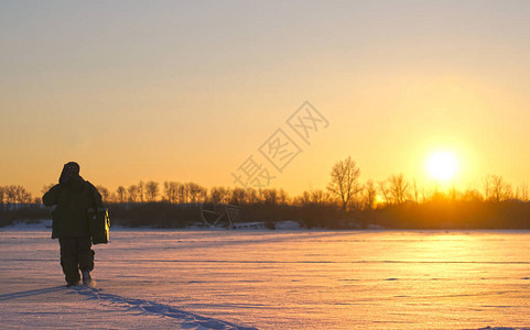 渔夫在日落时进行冬季钓鱼和冬季运动图片