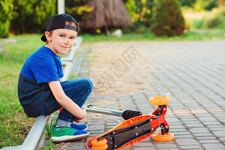 男孩从他的滑板车上摔下来孩子在骑滑板车时受伤不安的孩子在散步男孩图片
