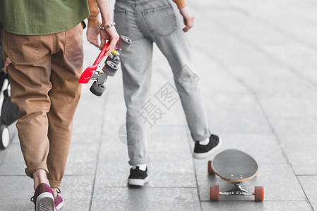 男人和女人拿着滑板在街上行走的剪影图片
