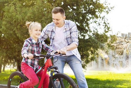 父亲在教他女儿骑自行车图片