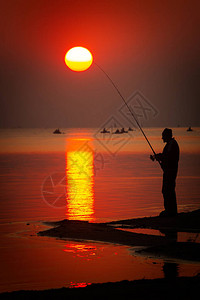 日落时旋转的钓鱼渔夫的剪影图片