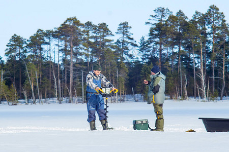冬季背景下的两名渔民用冰钻冰图片