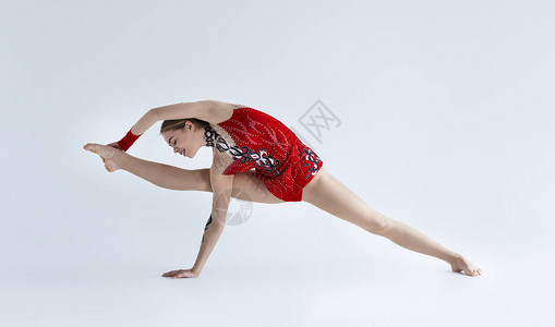 年轻体操运动员女青年拉和训练红色运动服白图片